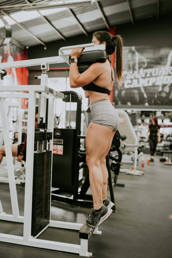 Chica en una máquina de gimnasio, haciendo sentadilla.