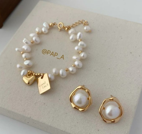 Pulsera de oro con perlitas y pendientes de oro con perlitas blancas encima de un cajón de color hueso muy bueno para regalos