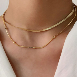 Collar dorado doble con perlitas encima de un cuello de una ,mujer