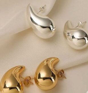 Pendientes de color dorado y plateado, encima de un manto de satín