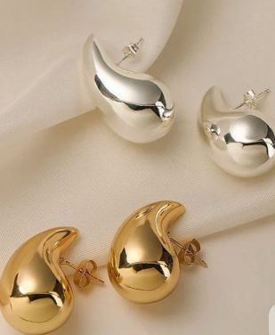 Pendientes de color dorado y plateado, encima de un manto de satín