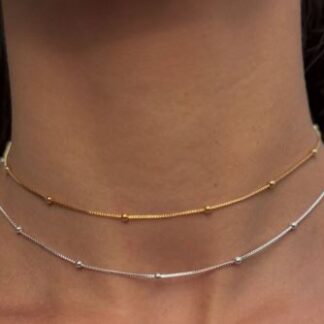 Collares de oro y plata con bolitas en su diseño, encima de el cuello de una mujer