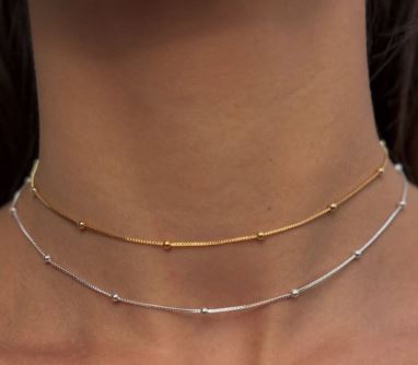 Collares de oro y plata con bolitas en su diseño, encima de el cuello de una mujer