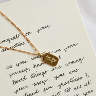 Un collar en dorado, en forma rectangular con las esquinas redondeadas y con una frase en el centro