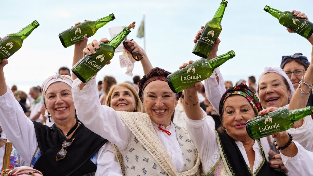 Imagen de un grupo de mujeres con vestimenta tradicional asturiana, participando en el récord de escanciado en Gijón, escanciando botellas de sidra de marca La Guaja
